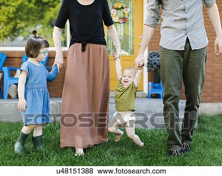 Parents with daughters (2-3, 12-17 months) standing on grass View Large Photo Image Stock Photo - Parents with daughters (2-3, 12-17 months) standing on grass. Fotosearch