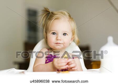 Stock Photo - Portrait of baby girl (12-17 months) eating lunch. Fotosearch