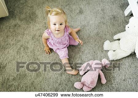 Stock Photo - Portrait of baby girl (12-17 months) sitting on floor. Fotosearch
