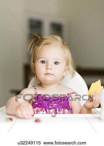 Stock Photography - Portrait of baby girl (12-17 months) eating lunch. Fotosearch