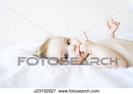 Stock Photo - Portrait of baby girl (6-11 Months) with finger in mouth. Fotosearch