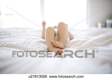 Portrait of baby girl (6-11 Months) lying down on bed with barefoot View Large Photo Image Stock Photograph - Portrait of baby girl (6-11 Months) lying down on bed with barefoot. Fotosearch