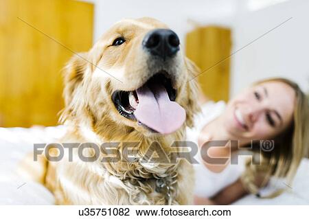 Stock Image - Portrait of blond woman with golden retriever. Fotosearch