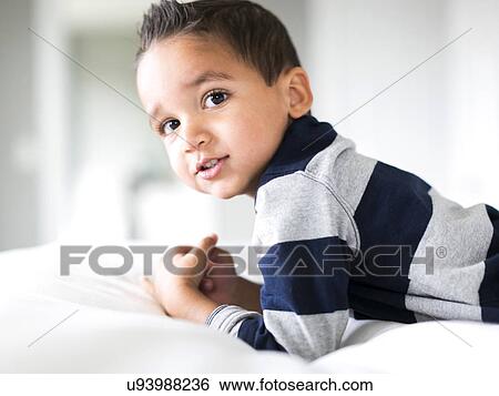 Stock Photograph - Portrait of boy (2-3) lying on bed. Fotosearch