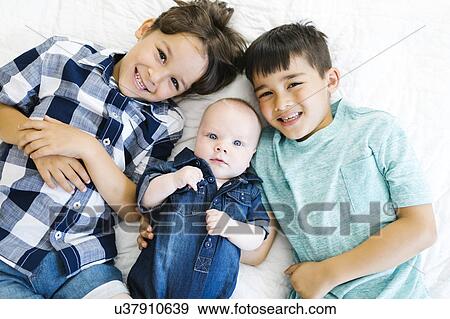 Portrait of brothers ( 2-5 months, 6-7, 8-9 ) lying on bed View Large Photo Image Stock Photo - Portrait of brothers ( 2-5 months, 6-7, 8-9 ) lying on bed. Fotosearch