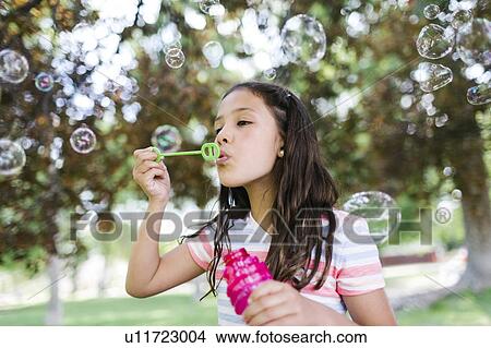 Picture - Portrait of girl ( 10-11 ) blowing soap bubbles. Fotosearch