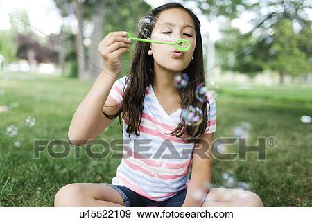 Portrait of girl ( 10-11 ) sitting in meadow and blowing soap bubbles View Large Photo Image Stock Photo - Portrait of girl ( 10-11 ) sitting in meadow and blowing soap bubbles. Fotosearch