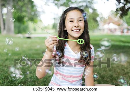Portrait of girl ( 10-11 ) sitting in meadow and blowing soap bubbles View Large Photo Image Stock Photography - Portrait of girl ( 10-11 ) sitting in meadow and blowing soap bubbles. Fotosearch