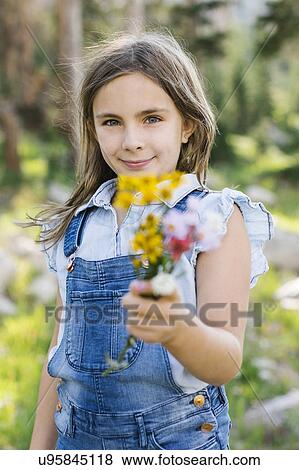 Portrait of girl (8-9) holding wildflowers View Large Photo Image Stock Photo - Portrait of girl (8-9) holding wildflowers. Fotosearch