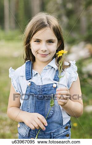 Stock Photography - Portrait of girl (8-9) holding wildflowers. Fotosearch