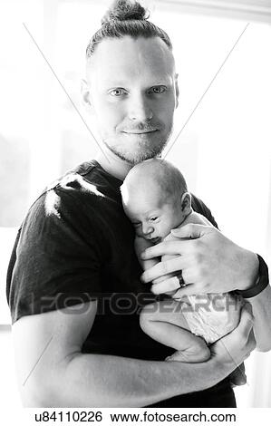 Stock Photograph - Portrait of man holding his on day son (0-1 months). Fotosearch