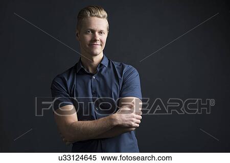 Stock Photography - Portrait of man with crossed arms on black background. Fotosearch