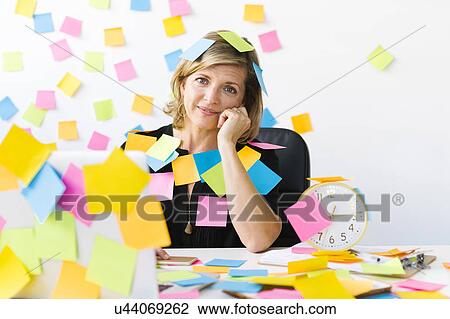 Stock Image - Portrait of Mature woman at office covered with adhesive notes. Fotosearch