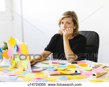 Stock Photography - Portrait of Mature woman at office overwhelmed by adhesive notes. Fotosearch