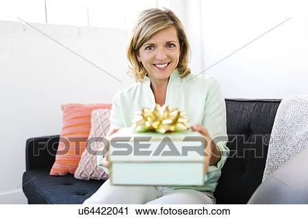 Stock Image - Portrait of Mature woman giving gift. Fotosearch