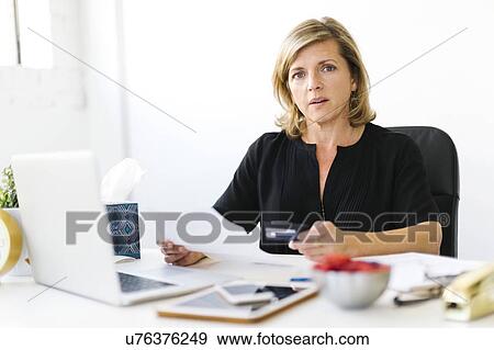 Stock Photo - Portrait of Mature woman paying bills. Fotosearch