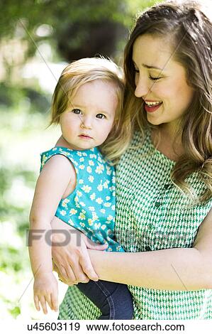 Stock Photo - Portrait of mother and baby girl (12-17 months) in backyard. Fotosearch