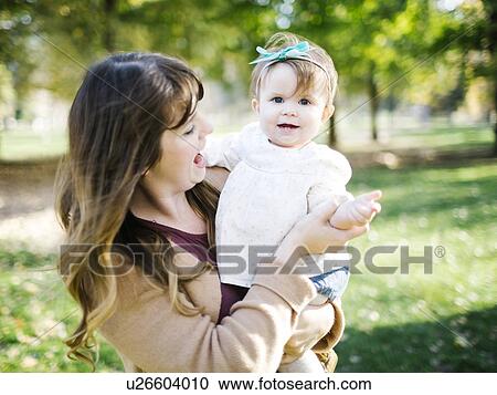 Portrait of mother carrying daughter (12-17 months) in park View Large Photo Image Stock Image - Portrait of mother carrying daughter (12-17 months) in park. Fotosearch