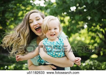 Stock Image - Portrait of mother carrying daughter (12-17 months). Fotosearch