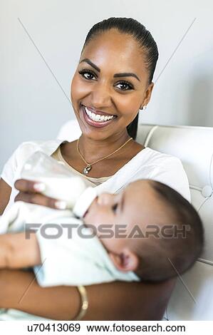 Stock Photo - Portrait of mother feeding baby boy (2-5 months). Fotosearch
