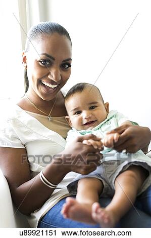 Stock Image - Portrait of mother holding baby boy (2-5 months). Fotosearch