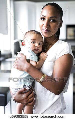 Stock Photo - Portrait of mother holding baby boy (2-5 months). Fotosearch