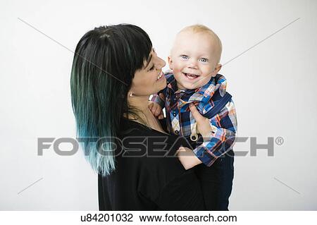 Stock Image - Portrait of mother holding son (12-17 months) against white background. Fotosearch