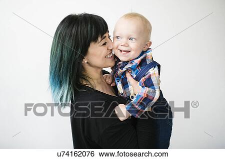 Stock Photograph - Portrait of mother holding son (12-17 months) against white background. Fotosearch