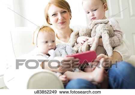 Portrait of mother using smart phone with daughters ( 12-17 months ) View Large Photo Image Stock Photo - Portrait of mother using smart phone with daughters ( 12-17 months ). Fotosearch