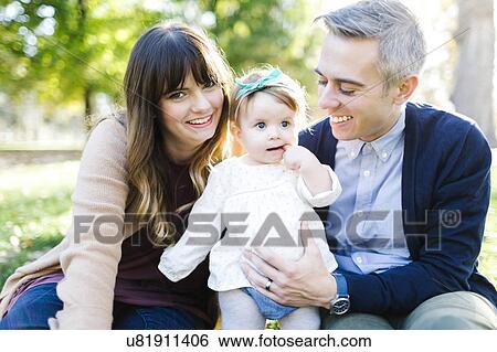 Portrait of parents with daughter (12-17 months) in park View Large Photo Image Stock Photograph - Portrait of parents with daughter (12-17 months) in park. Fotosearch
