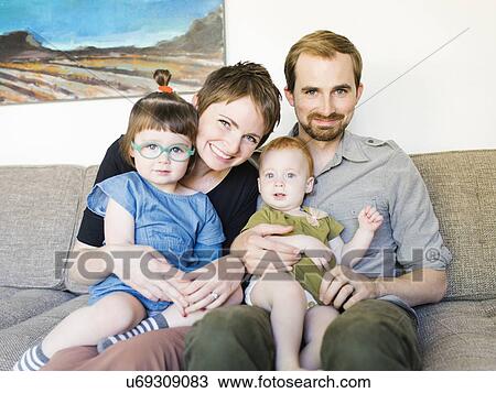 Portrait of parents with daughters (12-17 months, 2-3) sitting on sofa View Large Photo Image Stock Image - Portrait of parents with daughters (12-17 months, 2-3) sitting on sofa. Fotosearch