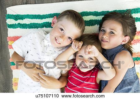 Portrait of siblings (2-3, 6-7) lying on carpet View Large Photo Image Stock Image - Portrait of siblings (2-3, 6-7) lying on carpet. Fotosearch