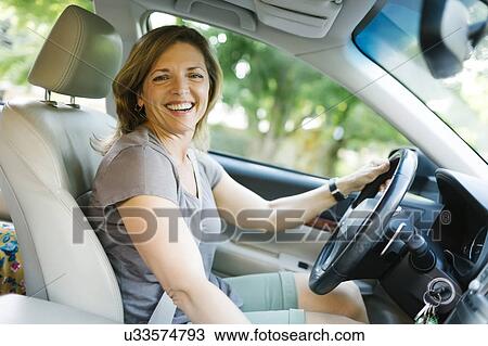 Stock Image - Portrait of smiling woman driving car. Fotosearch