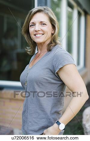 Stock Photograph - Portrait of smiling woman in front of house. Fotosearch