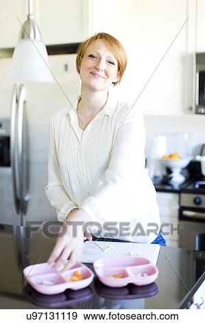 Stock Photo - Portrait of smiling woman preparing lunch. Fotosearch