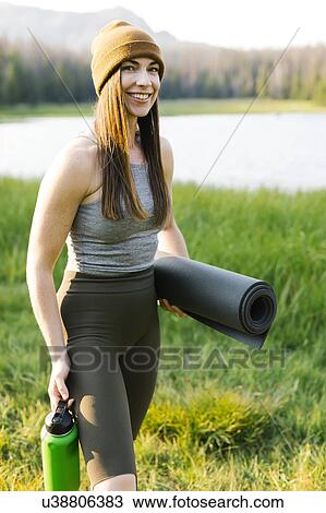 Stock Image - Portrait of woman carrying camping gear. Fotosearch