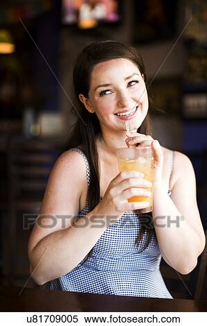 Stock Photography - Portrait of woman drinking juice in cafe. Fotosearch