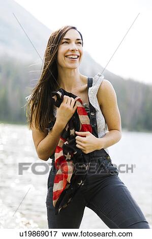 Stock Photo - Portrait of woman holding us flag by lake. Fotosearch