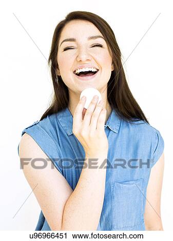Stock Image - Portrait of woman laughing and holding cotton pad. Fotosearch
