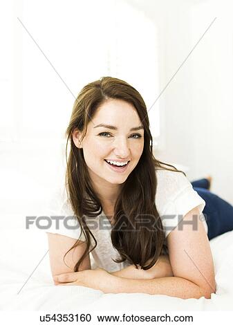 Portrait of woman lying on bed and smiling View Large Photo Image Stock Image - Portrait of woman lying on bed and smiling. Fotosearch