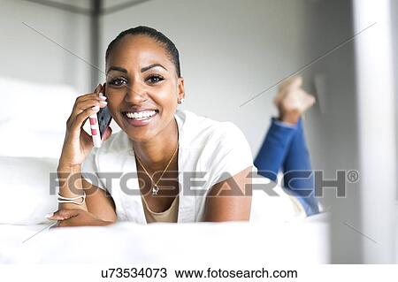 Portrait of woman lying on bed and using smart phone View Large Photo Image Stock Image - Portrait of woman lying on bed and using smart phone. Fotosearch