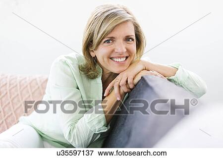 Stock Photo - Portrait of woman sitting on sofa. Fotosearch