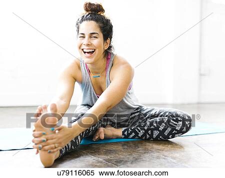 Stock Photography - Portrait of woman stretching on exercise mat. Fotosearch
