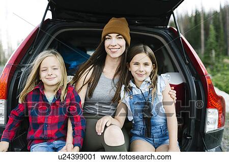 Stock Image - Portrait of woman with son (6-7) and daughter (8-9) in back of car. Fotosearch