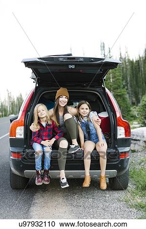 Stock Image - Portrait of woman with son (6-7) and daughter (8-9) in back of car. Fotosearch