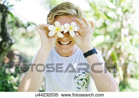 Portrait of young man holding gardenia flowers in front of eyes View Large Photo Image Stock Photography - Portrait of young man holding gardenia flowers in front of eyes. Fotosearch