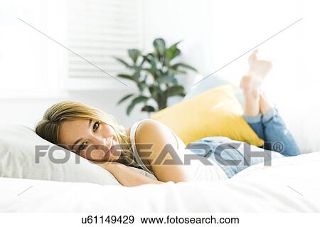 Portrait of young woman lying on bed View Large Photo Image Stock Photo - Portrait of young woman lying on bed. Fotosearch