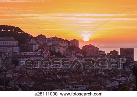 Stock Photo - Portugal, Lisbon, Sun rising above Old Town of Lisbon. Fotosearch