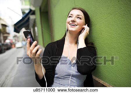 Stock Image - Puerto Rico, San Juan, Woman listening to music on street. Fotosearch