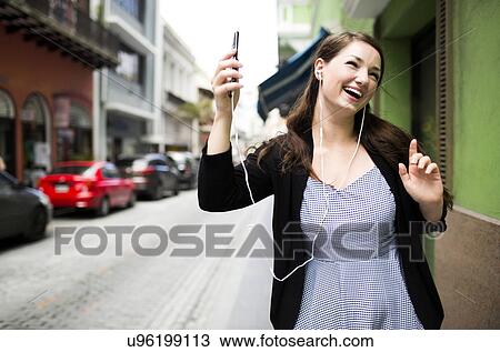 Stock Image - Puerto Rico, San Juan, Woman listening to music on street. Fotosearch